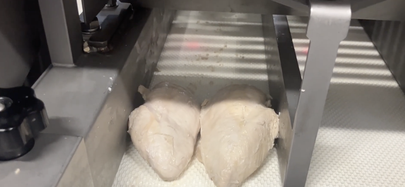Cooked chicken breast being loaded into the NCI slicer